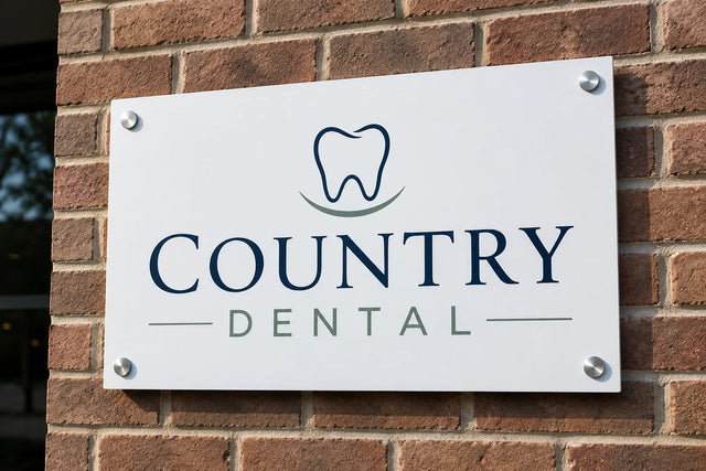 White aluminum composite wall sign for a dental office, mounted on a brick wall with silver standoff bolts