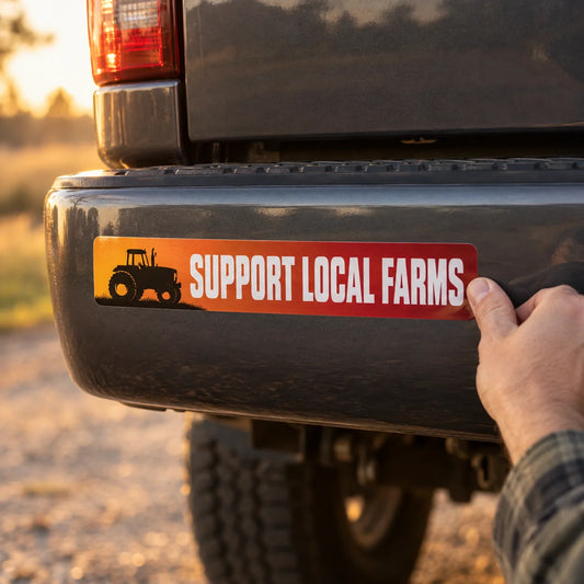 Custom full-color bumper sticker reading SUPPORT LOCAL FARMS being pressed onto the rear bumper of a gray pickup truck