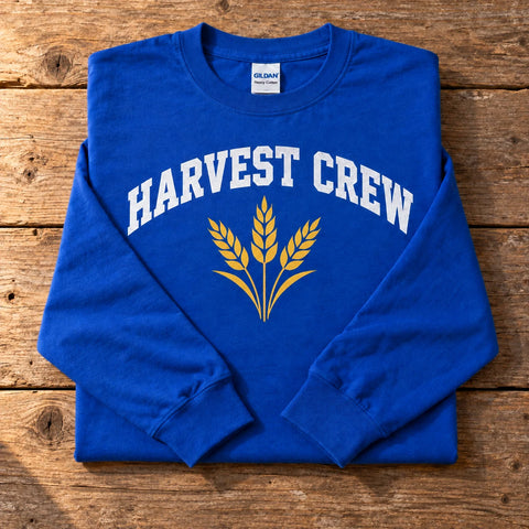 Custom Gildan Heavy Cotton long sleeve t-shirt in Royal with a full-color HARVEST CREW wheat DTF print, folded on a wood table