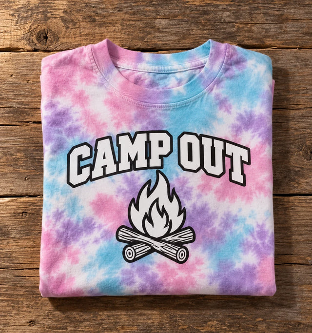 Custom Colortone youth tie-dye t-shirt in Cotton Candy with a full-color CAMP OUT campfire DTF print, folded on a wood table