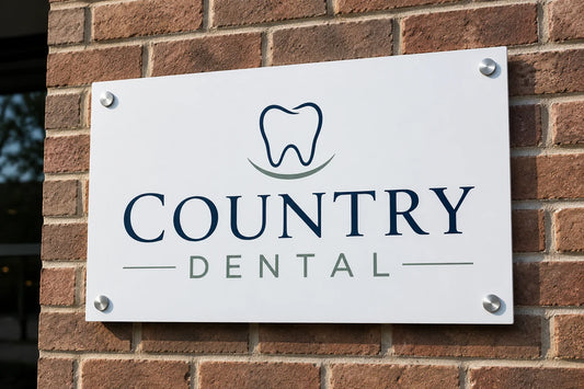 White aluminum composite wall sign for a dental office, mounted on a brick wall with silver standoff bolts