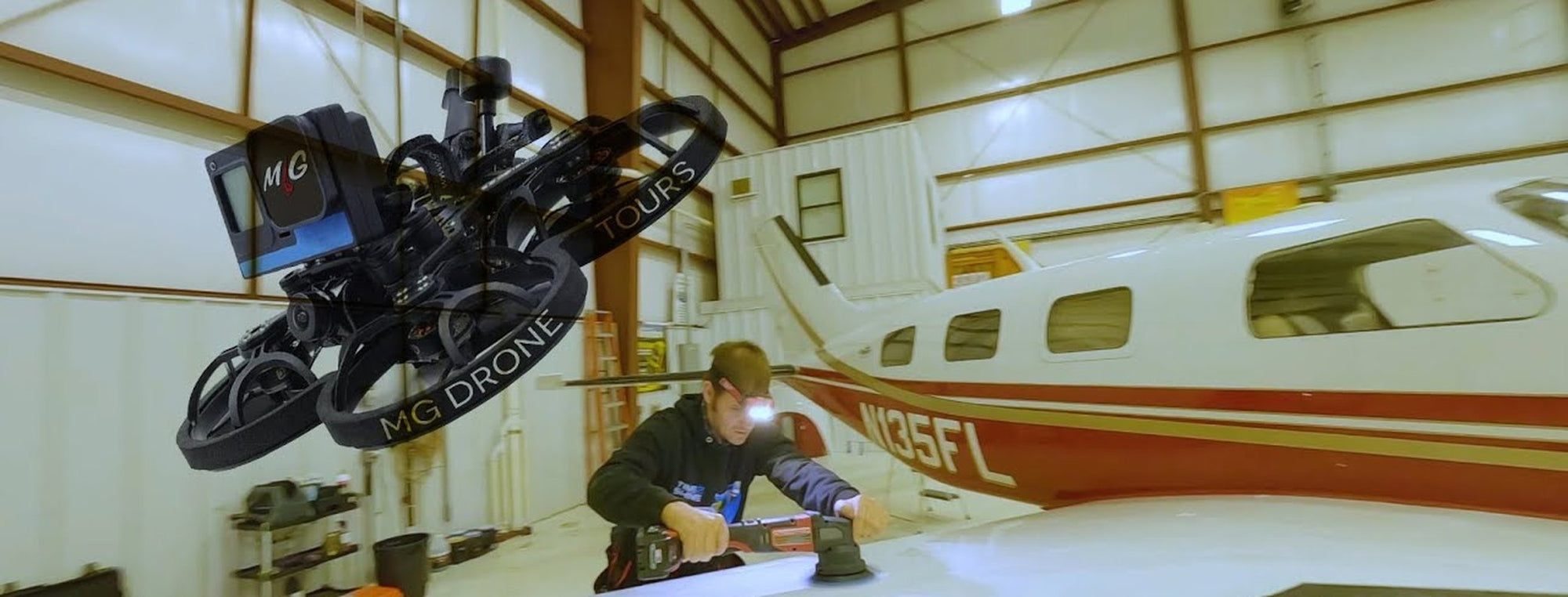 MG Drone Tours camera drone flying inside an aircraft hangar beside a plane